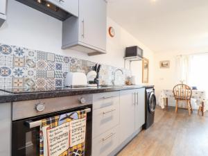 a kitchen with white cabinets and a dishwasher at Sandyfeet in Camborne