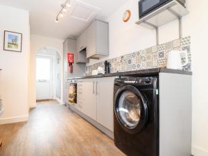 cocina con lavadora y secadora en una habitación en Sandyfeet, en Camborne