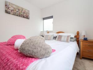 1 dormitorio con cama blanca y manta rosa en Sandyfeet, en Camborne