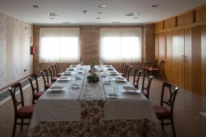 una lunga sala da pranzo con un lungo tavolo e sedie di Hospedium Hotel Doña Mafalda de Castilla a Plasencia