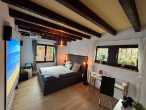 a bedroom with a bed and a desk and windows at Lovely house in a quiet place in Bôle