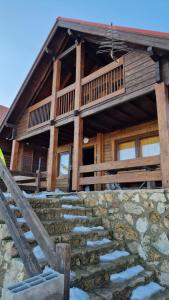 a log cabin with a stone staircase in front of it at Chalé Inn Star in Penhas da Saúde