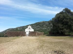 an old brick building with a mountain in the background at B&B Antico Telaio in Santa Maria Navarrese