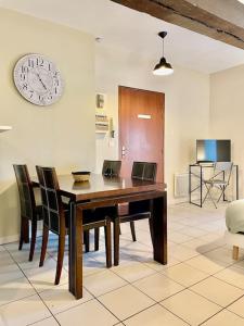 a dining room table with chairs and a clock on the wall at *Au centre de la ville haute G* ZEN LOC 6 in Provins