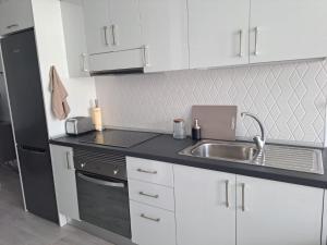 a kitchen with white cabinets and a sink and a refrigerator at Sirena Iris in El Cotillo