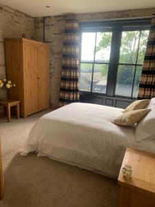 a bedroom with a white bed and a large window at The Weavers Shed in Huddersfield