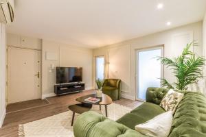 un soggiorno con divano verde e TV di AmazINN Places Gran Via VII a Madrid