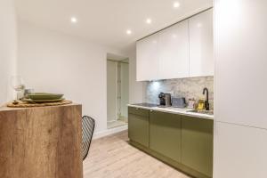 una cucina con armadietti verdi e bianchi e un bancone di AmazINN Places Gran Via VII a Madrid