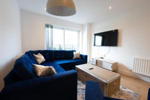 uma sala de estar com um sofá azul e uma televisão em Newly Built Spacious Apartment easily accessible to Luton Airport, Town centre and station em Luton