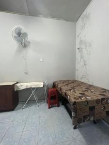 a room with a bed and a fan and a table at HOMESTAY NO.45 in Jitra