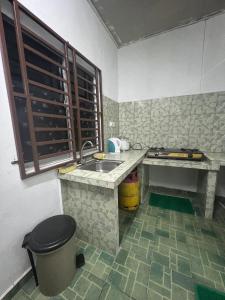 een kleine keuken met een wastafel en een raam bij HOMESTAY NO.45 in Jitra