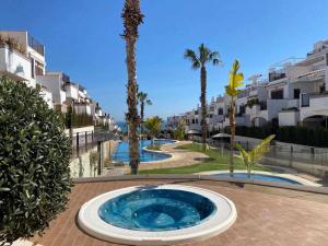 duży niebieski basen z palmami i budynkami w obiekcie Impresionante piso de planta baja cerca al mar w mieście Torrevieja