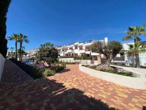 ceglany chodnik z palmami i budynek w obiekcie Impresionante piso de planta baja cerca al mar w mieście Torrevieja