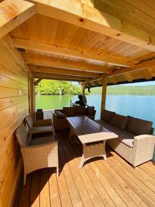 a wooden deck with a couch and a table on a boat at Floating House Perućac in Perućac