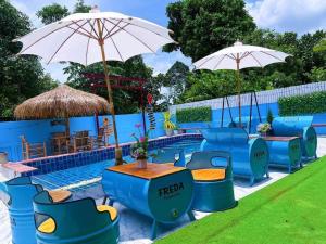 una piscina con sillas y sombrillas azules en FREDA poolvilla, en Ban Khlot