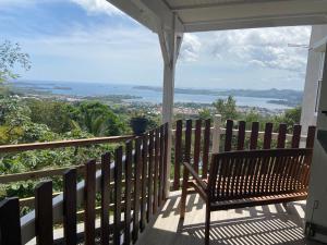 un banco en un porche con vistas al océano en Location vacances sur morne ventilé avec vue mer en Martinique en Le Robert