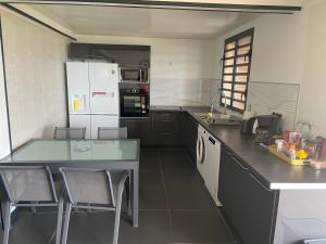 eine Küche mit schwarzen Arbeitsflächen und weißen Geräten in der Unterkunft Location vacances sur morne ventilé avec vue mer en Martinique in Le Robert