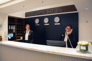 two people standing at the counter of a hotel at Ribera Sur Hotel Mar del Plata in Mar del Plata