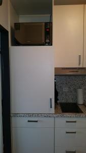 a white refrigerator in a kitchen with a microwave at FeWo Eggers 1 in Burgtiefe auf Fehmarn 