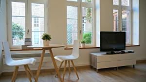 sala de estar con mesa, TV y ventanas en Little Suite - Oscar, en Lille