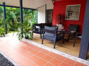 a patio with chairs and a table and a red wall at Villa de 2 chambres avec piscine privee jardin clos et wifi a Le Lamentin in Le Lamentin