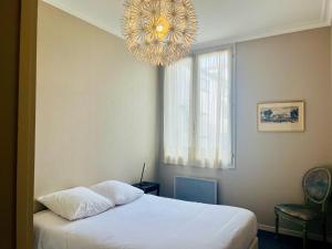 um quarto com uma cama branca e um lustre em L'Appart Du Vieux Port em La Rochelle