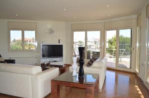 a living room with a white couch and a tv at Villa Mar i Vent in L'Ampolla