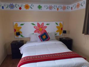 a bedroom with a white bed with flowers on the wall at Reinbo Garden in Cusco