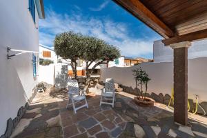 a patio with two chairs and a wall at Sottotorre 1 in Calasetta