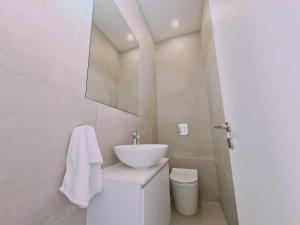 uma casa de banho branca com um lavatório e um WC em STAY Sunshine Aura em Protaras
