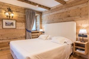a bedroom with a white bed and wooden walls at Auberge de La Maison in Courmayeur