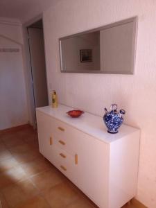 una cómoda blanca con un jarrón azul encima en LES VIGNES ET LA PINEDE PRES DE LA PLAGE en Saint-Tropez