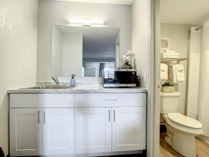 a white bathroom with a sink and a microwave at Stayable Kissimmee West in Kissimmee