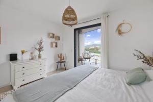a white bedroom with a bed and a window at Agosta Sea View in Porticcio