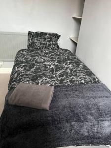 2 bed house near Sefton Park & Lark Lane في ليفربول: غرفة نوم بسرير وبطانية بيضاء وسوداء