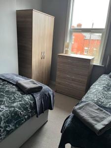 2 bed house near Sefton Park & Lark Lane في ليفربول: غرفة نوم بسرير وخزانة ونافذة