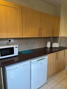 La cuisine est équipée d'un four micro-ondes blanc et d'un réfrigérateur. dans l'établissement 2 bed house near Sefton Park & Lark Lane, à Liverpool