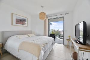 a bedroom with a bed and a tv and a balcony at Agosta Sea View in Porticcio