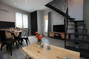 ein Wohnzimmer mit einem Tisch und einer Wendeltreppe in der Unterkunft Maison Le Lodge- Centre Doué la Fontaine proche zoo in Doué-la-Fontaine