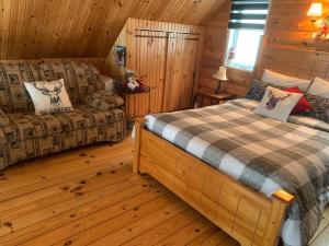 a bedroom with a bed and a couch in a cabin at Chalets Garou in St-Ferdinand