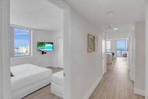 a white room with a bed and a television on a wall at Condo 3 Bedrooms 2 min from the beach in Hallandale Beach