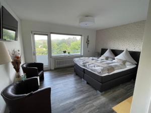 a bedroom with a bed and two chairs at Gästehotel Lucendi Premium Lounge in Hohenleimbach