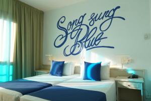 two beds in a hotel room with a sign on the wall at Lloret Vibe Affiliated by FERGUS in Lloret de Mar