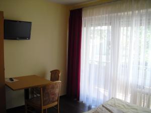 a room with a table and a window with a television at Boardingroom in Filderstadt