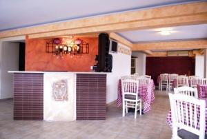 a room with tables and white chairs and a bar at Palatino in Loutra Edipsou