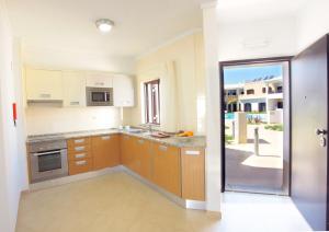a kitchen with wooden cabinets and a sliding glass door at Sagres Time Apartamentos in Sagres