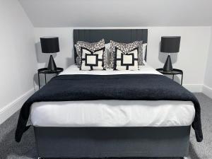 a bedroom with a large bed with black and white pillows at Tettenhall Village Townhouse in Wolverhampton