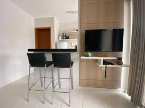 a kitchen with a bar with four chairs and a television at Flat 123 - Veredas - 300 metros Hot Park - Vista Piscina in Rio Quente