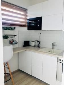 een witte keuken met een wastafel en een magnetron bij Belvárosi Stúdió Apartman in Kecskemét