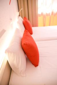two red and white pillows sitting on a bed at Lloret Vibe Affiliated by FERGUS in Lloret de Mar